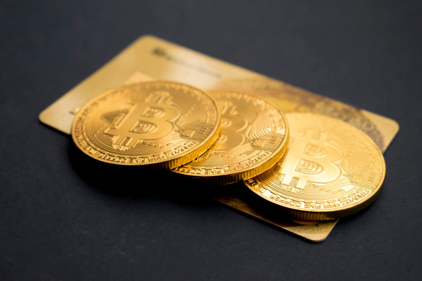 Gold Bitcoin tokens resting on a dark surface, illustrating crypto balances earning interest on be1crypto.com